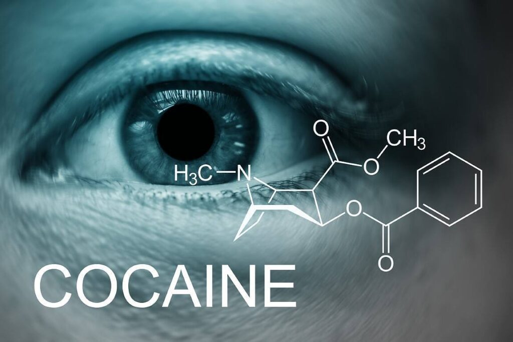 Close-up of a human eye with dilated pupil, overlaid with the chemical structure of cocaine and the word 'COCAINE' in bold text, illustrating cocaine addiction impact on the body