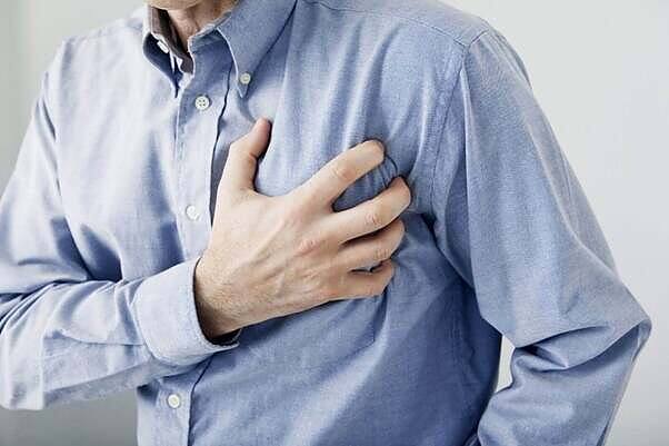 Man clutching chest, highlighting heart risks associated with mixing Viagra and cocaine.|Close-up of a person's hand arranging lines of white powder, likely cocaine, on a reflective surface, illustrating dangerous drug use behaviors