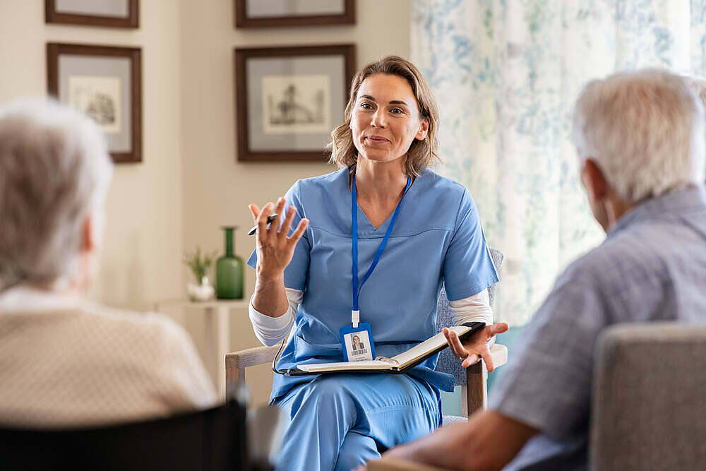Female nurse in blue scrubs explaining to elderly couple in a care home setting, possibly discussing medication or treatment options.|Two boxes of Night Nurse medication, one for liquid form and one for capsules, showing packaging with green cross symbol and ingredient information|night nurse liquid tablets|Man blowing nose into tissue next to Night Nurse medication boxes for liquid and capsules, highlighting cold symptoms and over-the-counter treatments