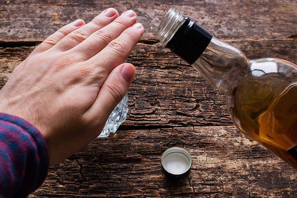 Hand gesture refusing alcohol, blocking whiskey bottle on wooden table, symbolizing quitting drinking|Infographic showing 3 stages of severe alcohol withdrawal: Stage 1 (8 hours) with initial symptoms, Stage 2 (1-3 days) with hallucinations and seizures, Stage 3 (3
