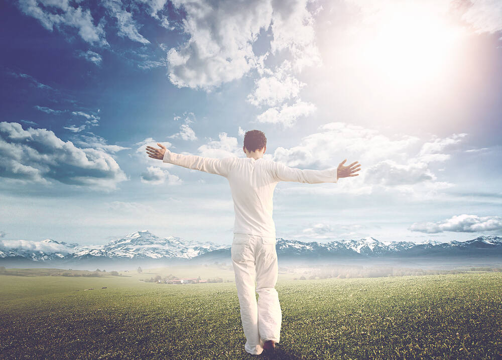 Man in white clothing with arms outstretched, facing mountains and bright sky, symbolizing freedom and recovery after rapid opiate detox|Wooden figurine with bowed head and chaotic thoughts represented by scribbles, symbolizing the mental challenges during cocaine detox and withdrawal